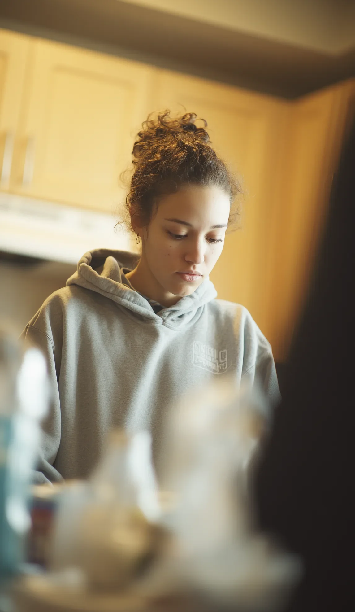 the-station-supported-recovery Young woman in a hoodie preparing food in a supportive recovery kitchen environment, representing community-based substance use recovery services.